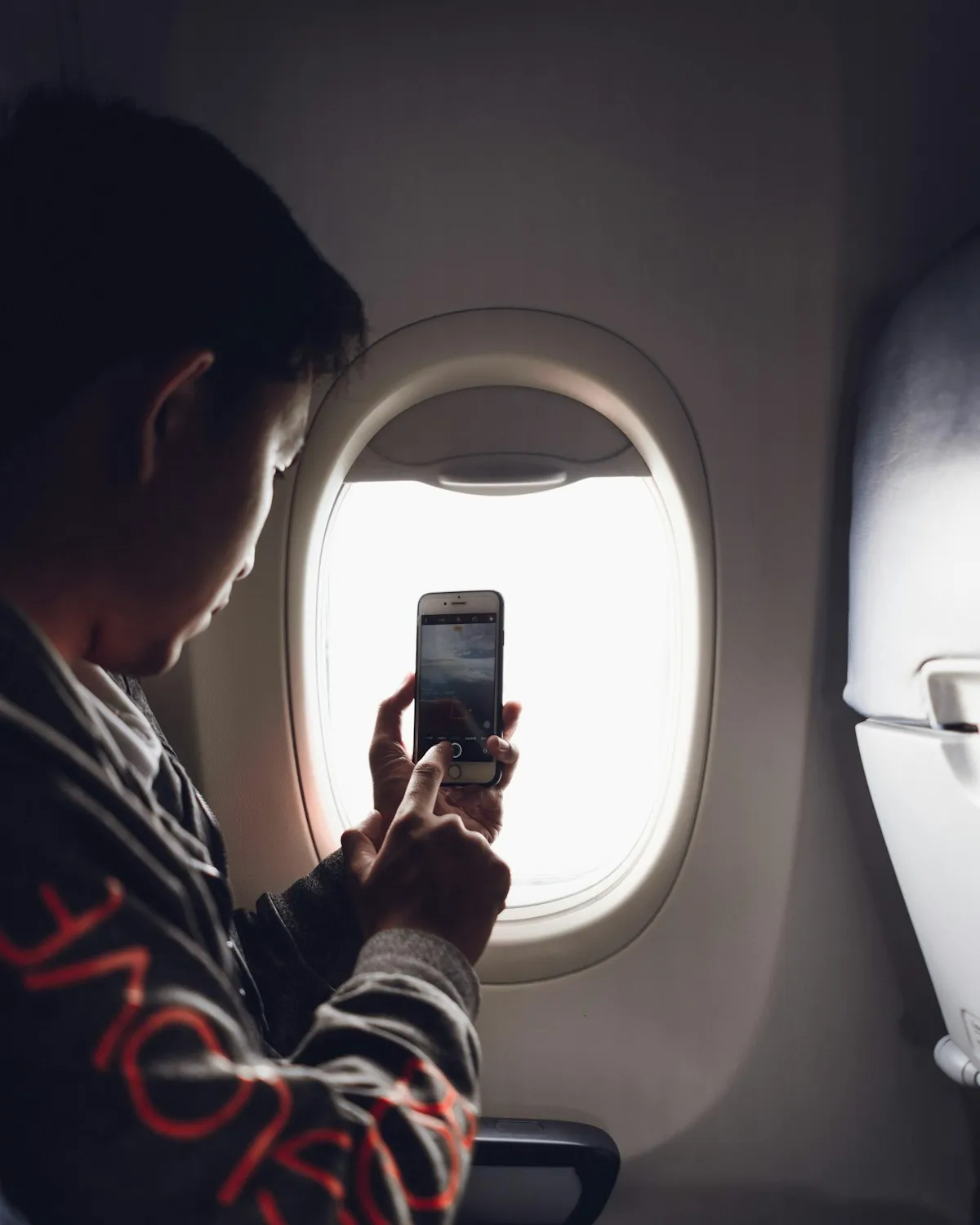 Traveler checking a smartphone while seated beside an airplane window