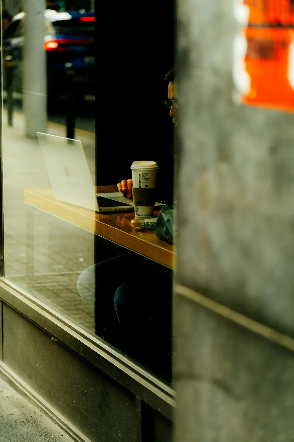 Traveler working on a laptop in a sunlit cafe, coffee beside the keyboard